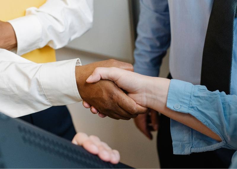 Two people shaking hands across a desk